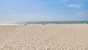 Ein weiter Sandstrand mit klarem Himmel und ruhiger See.
