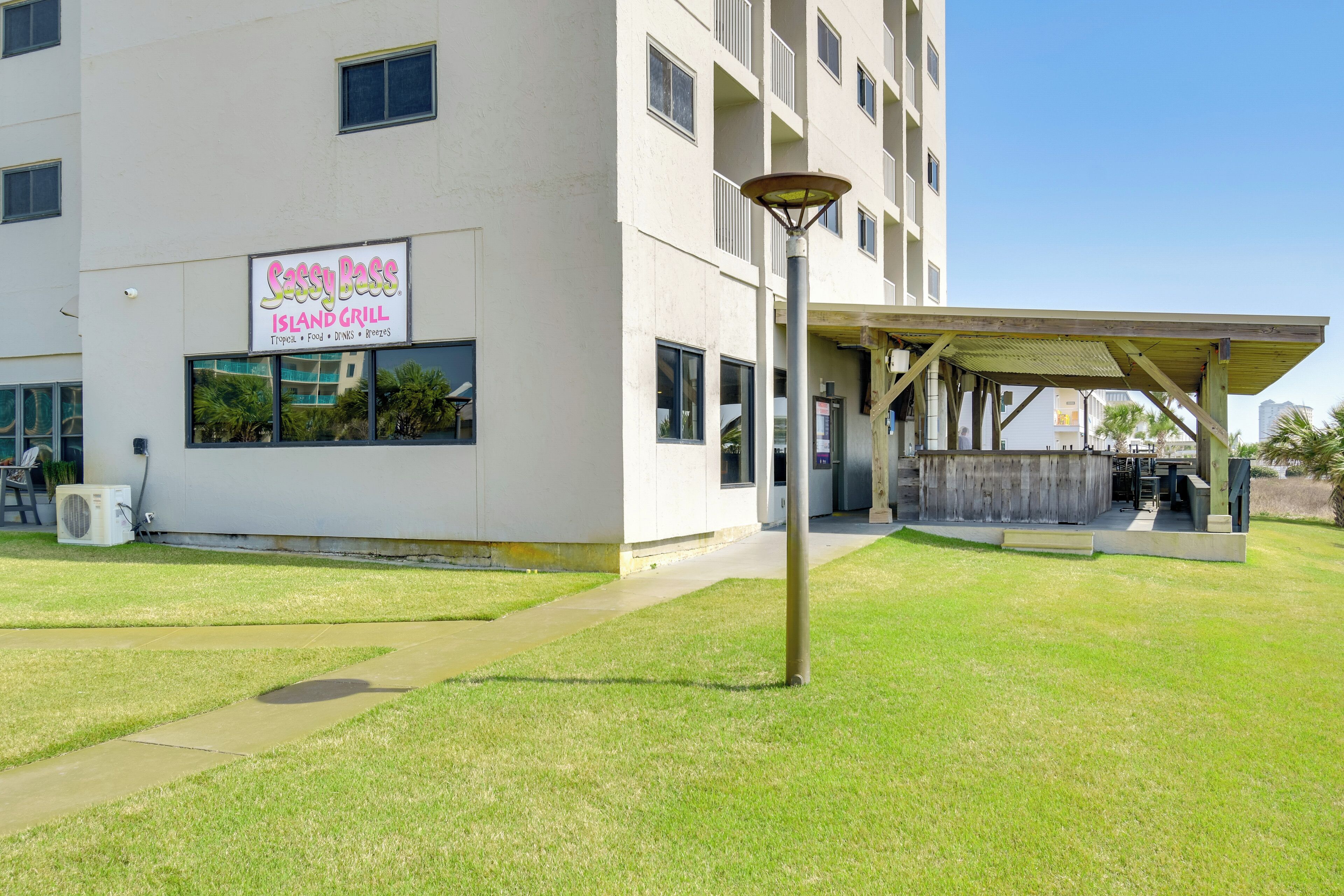 A building with a sign for "Sassy Place Island Grill" offering food, drinks, and beers.