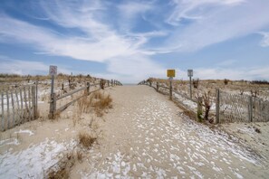 A sandy beach path with wooden fences and signs, leading to the ocean. - Steps to Beach: Townhome w/ Balcony in Ocean City (Ocean City)