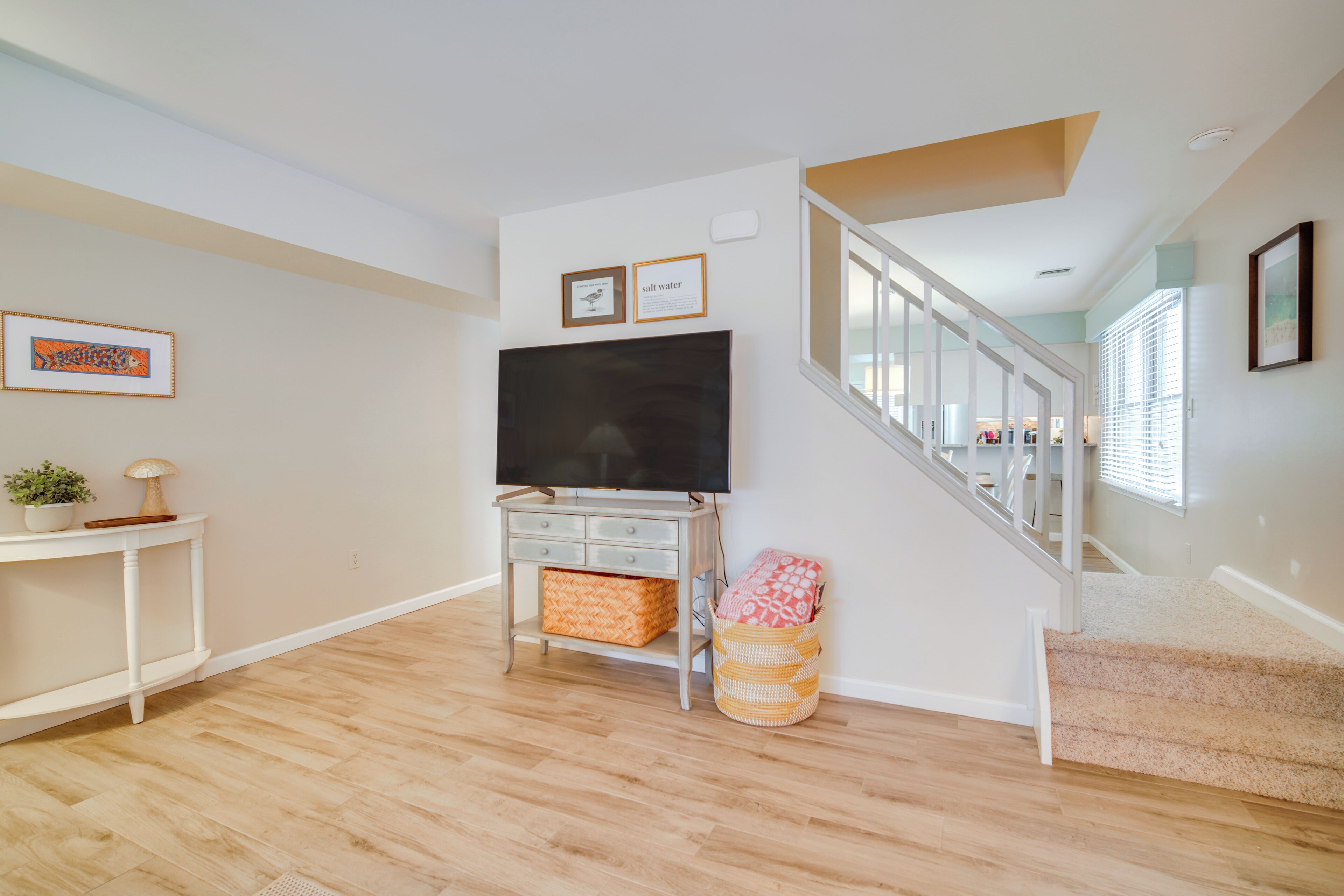 A living room with a TV, a staircase, and a wall-mounted picture frame.
