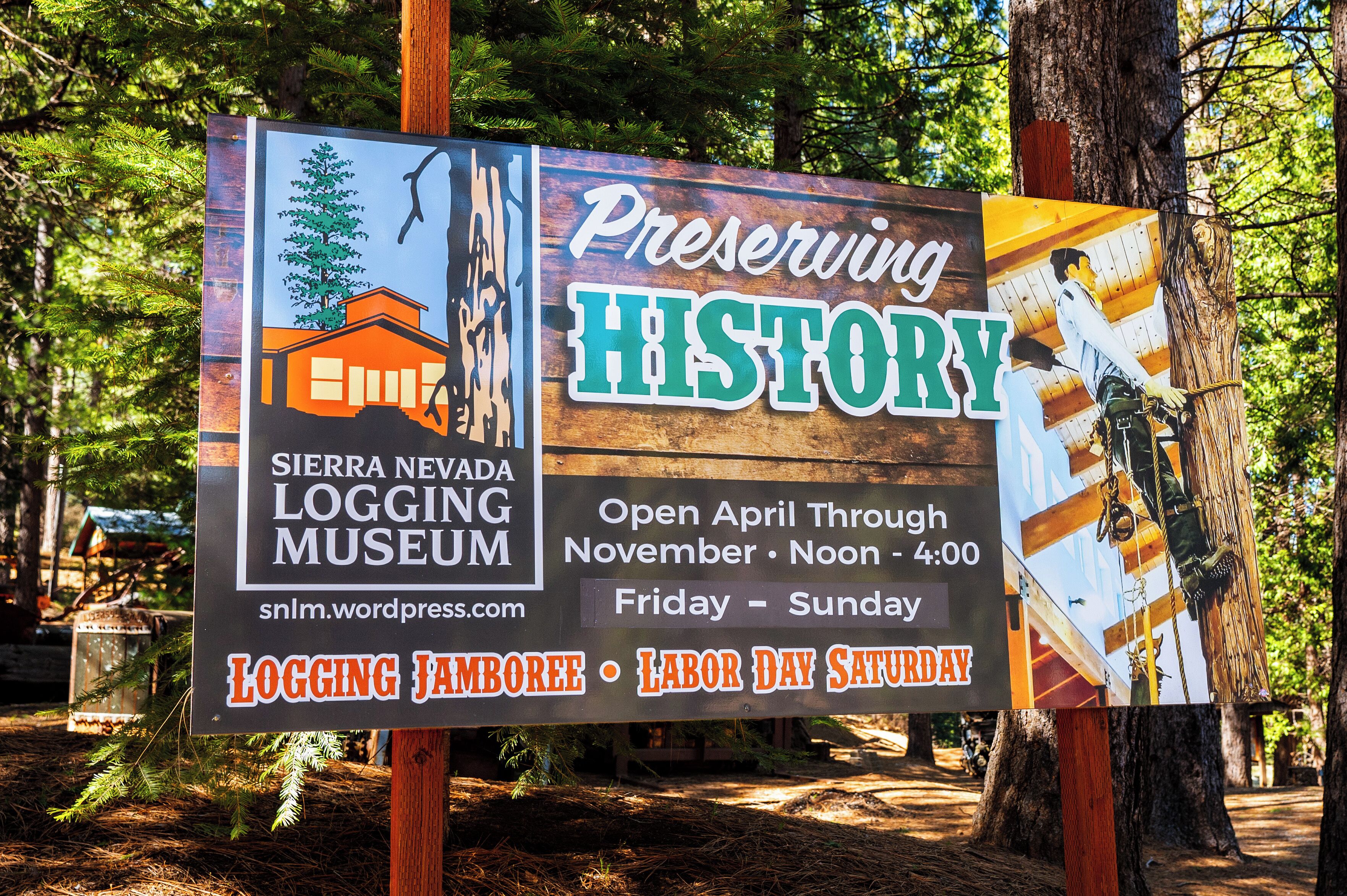 A sign for the Sierra Nevada Logging Museum, open from April through November, with a focus on logging history.
