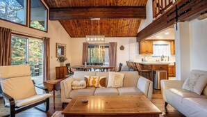 Un vaste espace de vie doté d’un plafond en bois, d’une table à manger et d’un canapé.