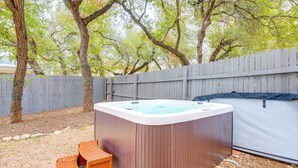 A hot tub with a wooden exterior, surrounded by a wooden fence and trees. - 6 Mi to Lake Travis: Spacious Cedar Park Home! (Cedar Park)