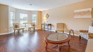 A spacious living room with hardwood flooring, a glass-top coffee table, and two armchairs. - 6 Mi to Lake Travis: Spacious Cedar Park Home! (Cedar Park)