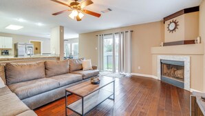 A living room with a sectional sofa, a coffee table, a fireplace, and a ceiling fan. - 6 Mi to Lake Travis: Spacious Cedar Park Home! (Cedar Park)