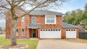 A two-story brick house with a front garage, a tree in the front yard, and a well-maintained lawn. - 6 Mi to Lake Travis: Spacious Cedar Park Home! (Cedar Park)