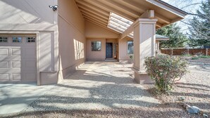 Ein Haus mit überdachter Veranda, Garage und einem Schotterweg.