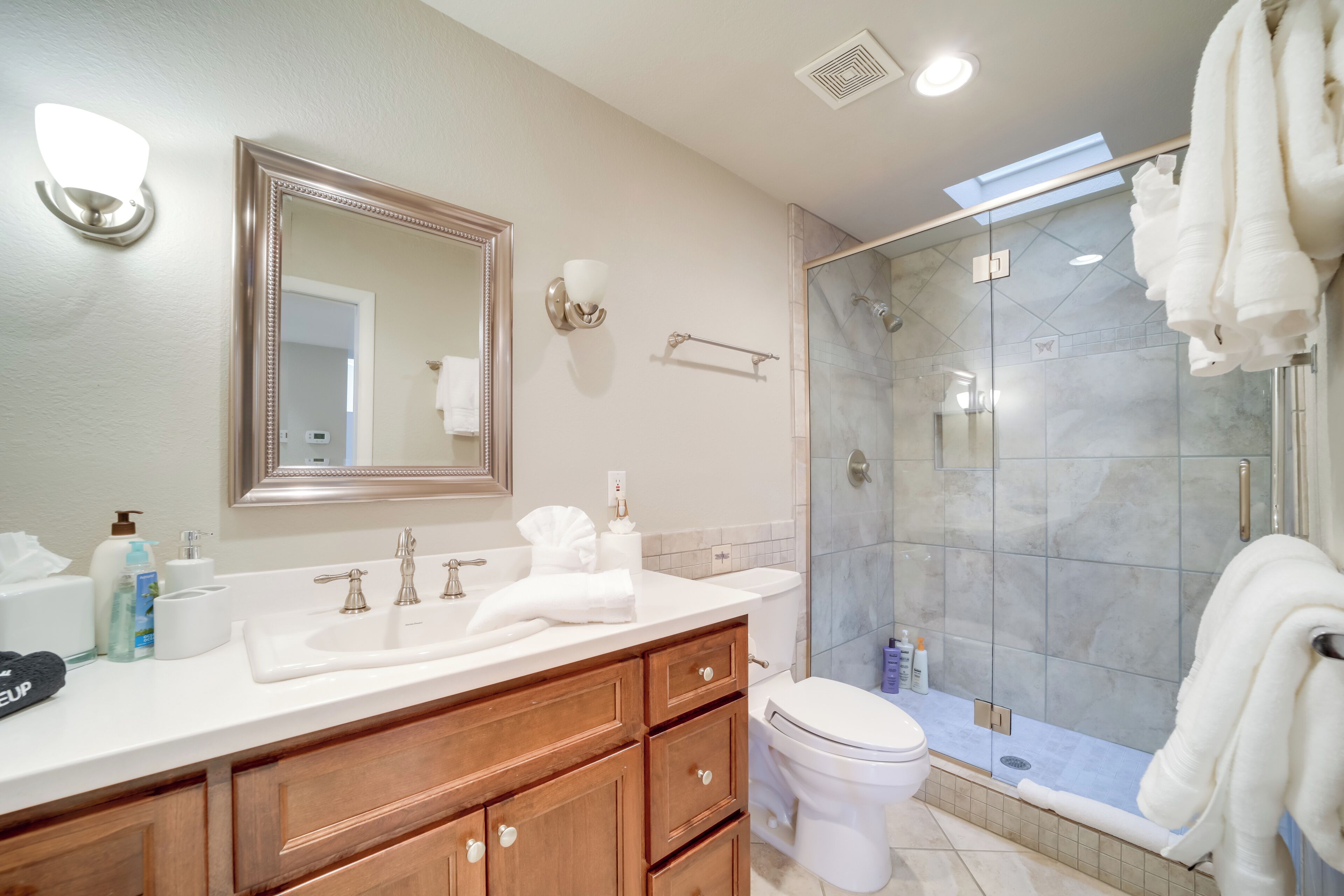 Een moderne badkamer met een grote spiegel, wastafel en een ruime douche.