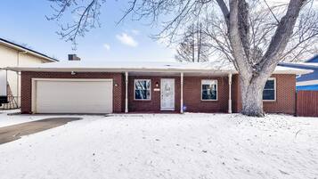 Situated in a serene setting, this house features a single-story design with a large garage door, front door, and side entrance.