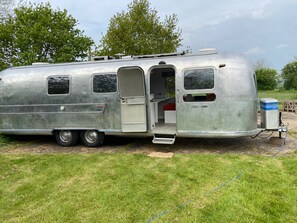 Ein silberner Wohnmobil mit Schiebetür, einer kleinen Küchenzeile und einer Schlafkoje.