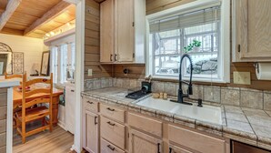 Una cocina con armarios de madera, un fregadero y una ventana con persianas.