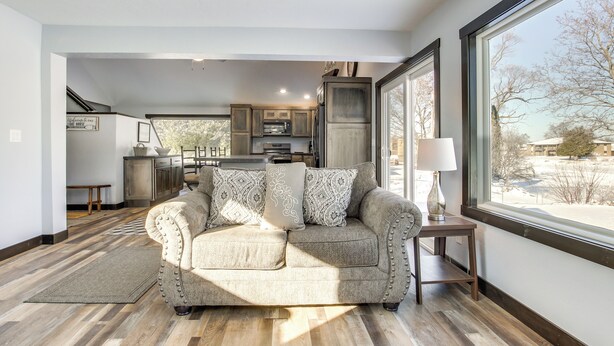 A modern living room with a sofa, a rug, and a window with a view of the outdoors. - Boat Dock: Riverfront Oconto Home! (Oconto)