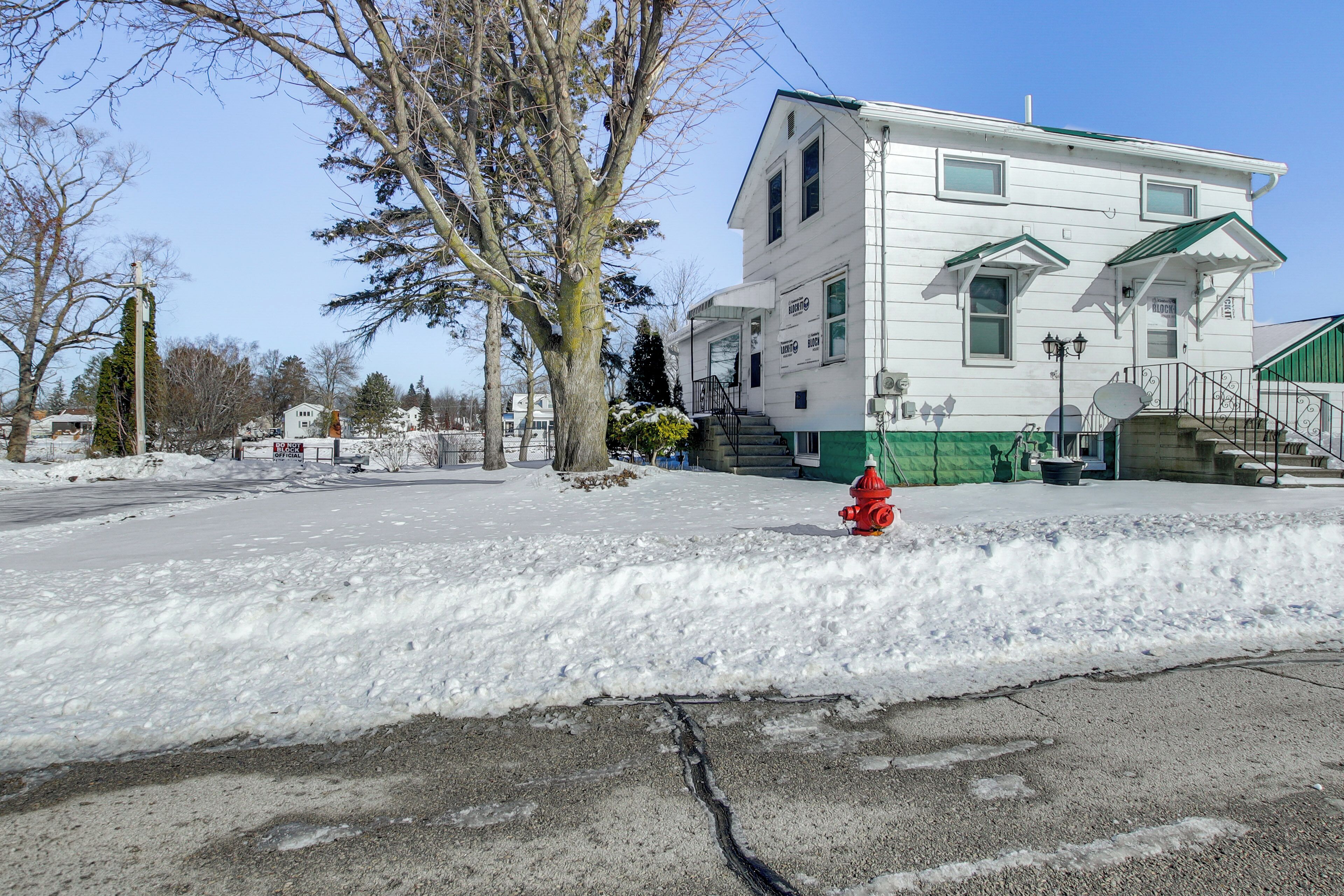 Un edificio bianco con tetto verde, un idrante rosso e terreno innevato.