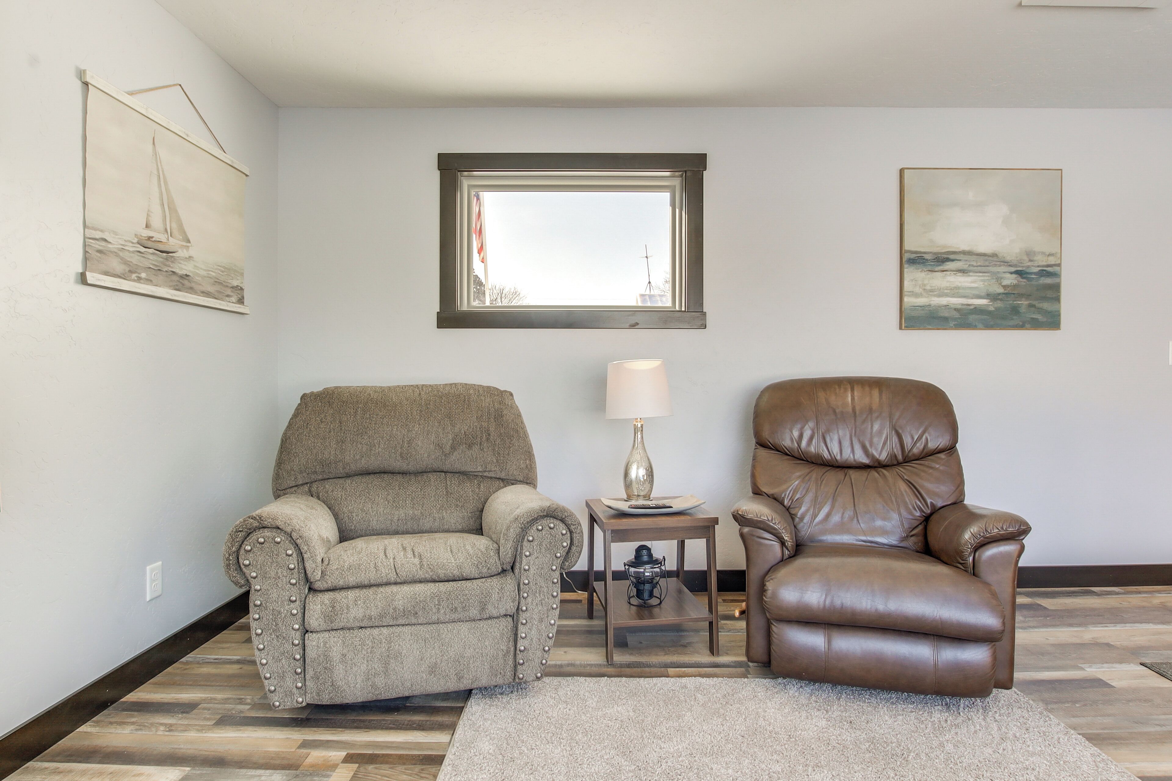 A living room with two armchairs, a lamp, and artwork on the walls.