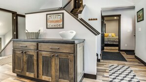 A staircase leading to a bedroom with a bed, a wooden cabinet with drawers, and a wall sign. - Boat Dock: Riverfront Oconto Home! (Oconto)