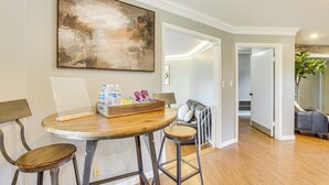 A dining area with a round table, two barstools, a laptop, and a tray of snacks. - 4 Mi to Dtwn Tuscaloosa: Home w/ Cozy Den! (Tuscaloosa)