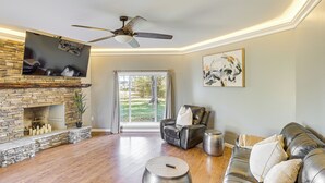 A spacious living room with a stone fireplace, leather sofa, and a flat-screen TV mounted above it. - 4 Mi to Dtwn Tuscaloosa: Home w/ Cozy Den! (Tuscaloosa)