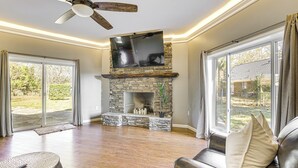 A spacious living room with a stone fireplace, leather sofa, and a ceiling fan. - 4 Mi to Dtwn Tuscaloosa: Home w/ Cozy Den! (Tuscaloosa)