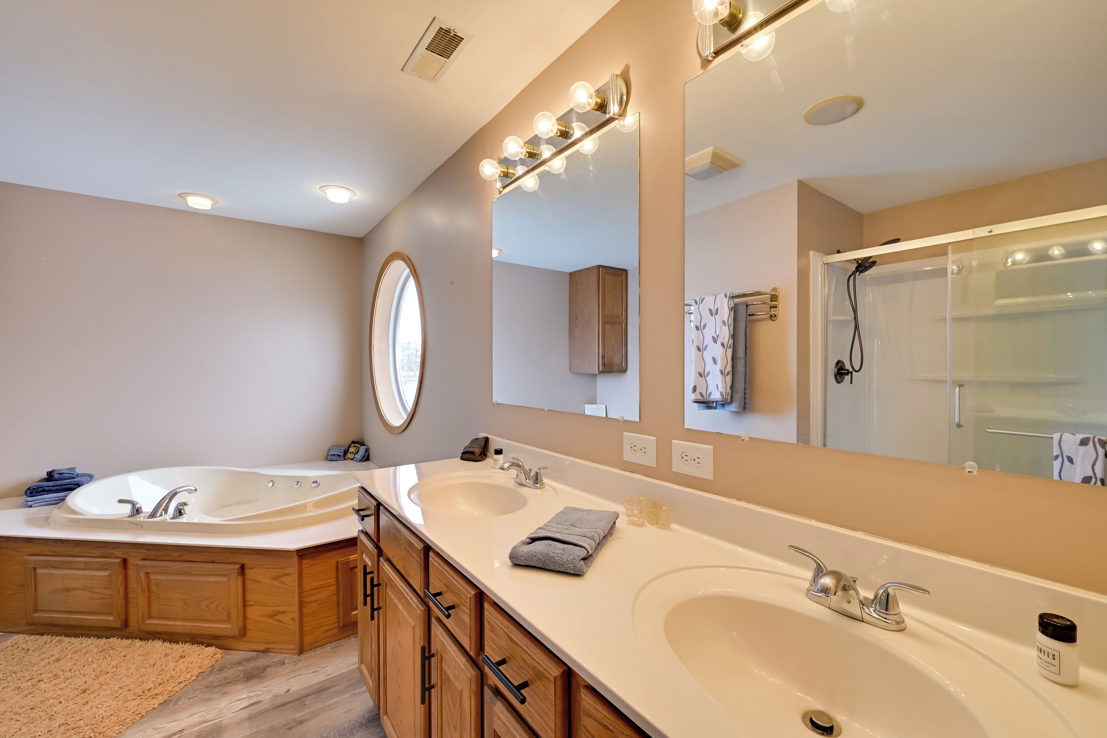 A modern bathroom with two sinks, a large mirror, and a walk-in shower.
