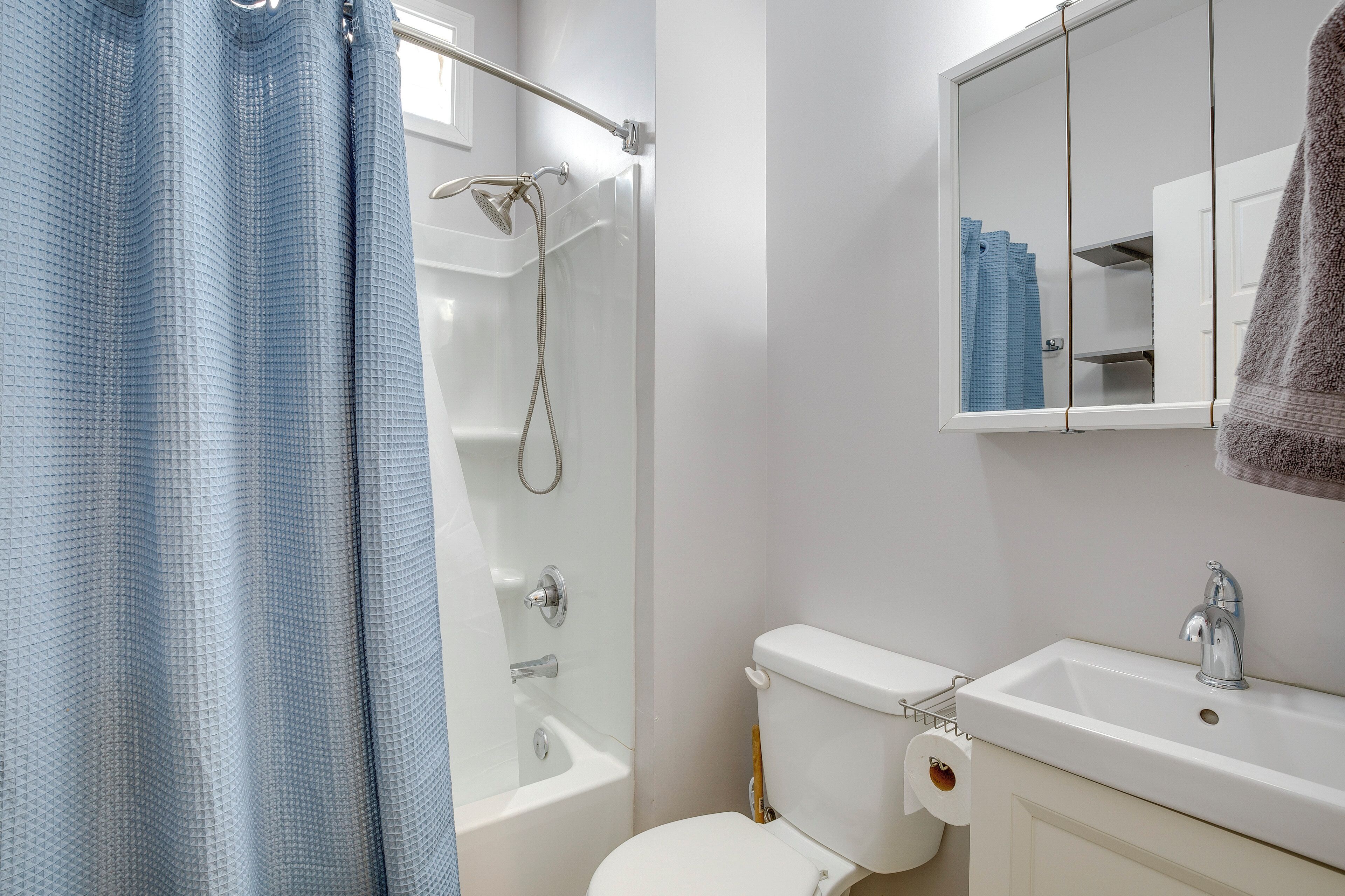 A bathroom with a bathtub, toilet, sink, and a mirror above the sink.