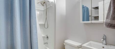 A bathroom with a bathtub, toilet, sink, and a mirror above the sink.