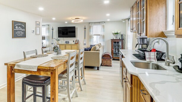 Een moderne keuken met houten kastjes, een eethoek met een tafel en stoelen, en een woonkamer met een bank en televisie.