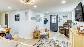 Een woonkamer met een bank, een stoel, een vloerkleed en een televisie.
