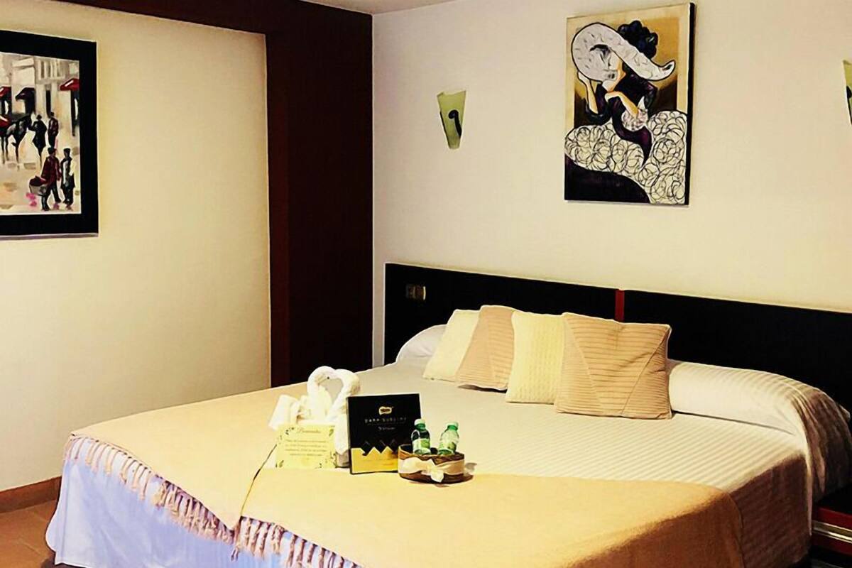 Une chambre d’hôtel avec un grand lit, une tête de lit et un tableau au mur.