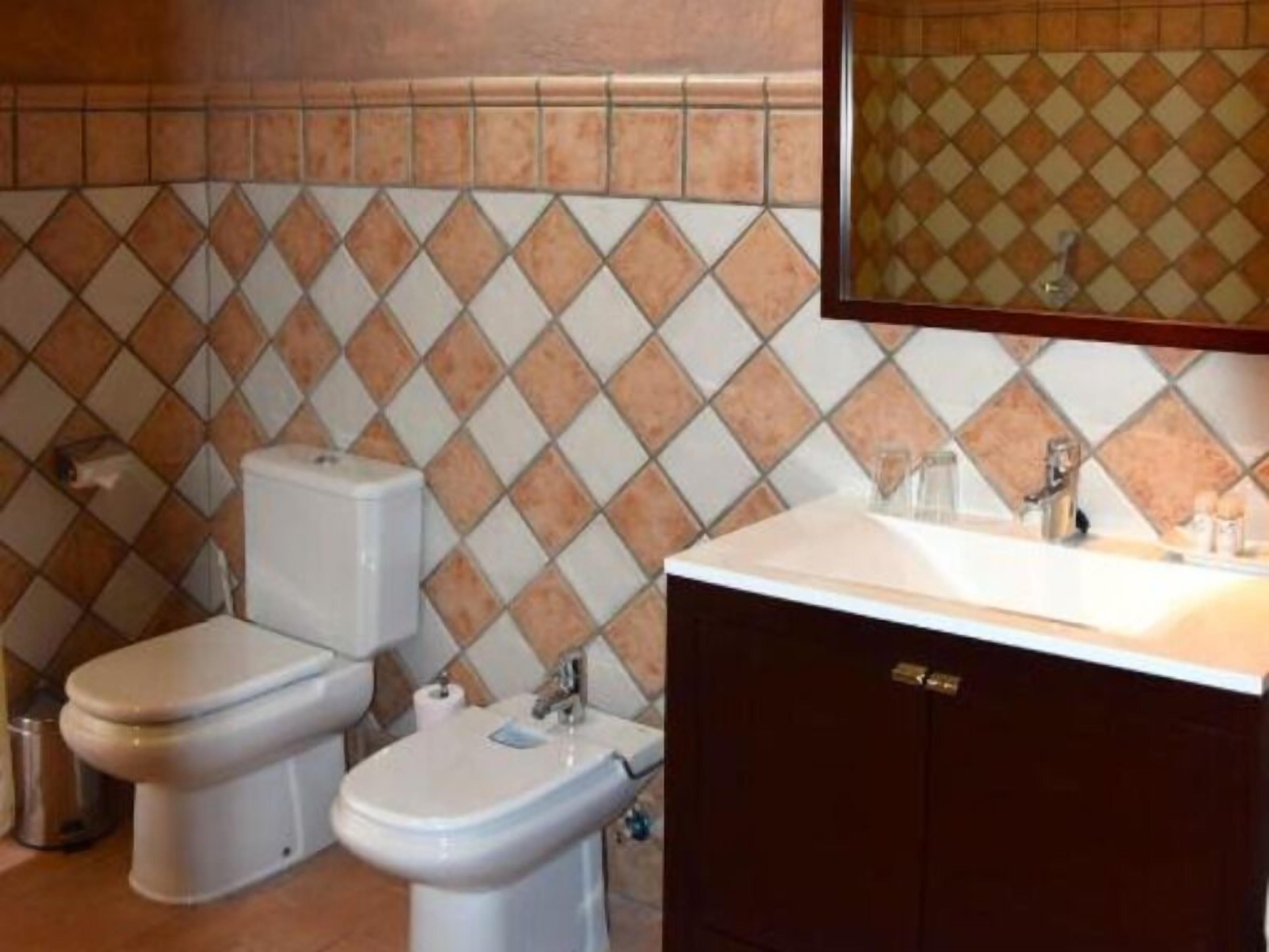A bathroom with two toilets, a sink, and a mirror.