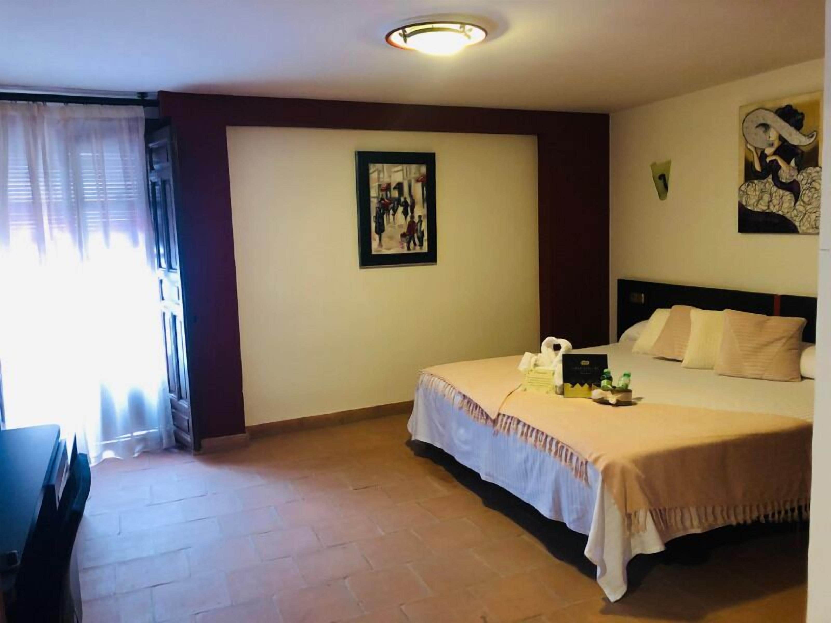 Una habitación de hotel con cama, escritorio y ventana con cortinas.