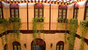 Ein Innenhof mit Ziegelmauern, Bogenfenstern und hängenden Weinreben.