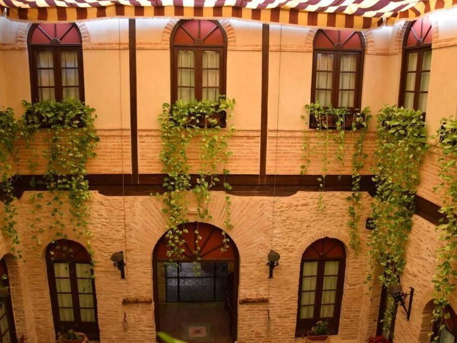 A courtyard with brick walls, arched windows, and hanging vines.