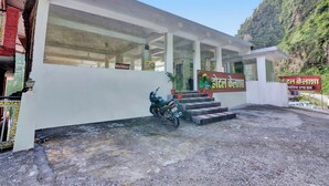 A building with a signboard in a foreign language, a staircase leading to the entrance, and a parked motorcycle.