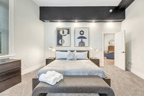 Ein modernes Schlafzimmer mit Bett, Nachttischen, einer Kommode und Bildern an der Wand.