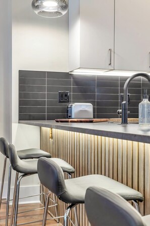 Eine moderne Küche mit einer zentralen Kochinsel, Barhocker, einem Toaster und einem Spülbecken.