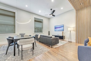 A modern living room with a dining table, sofa, and a ceiling fan.