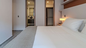 A hotel room with a large bed, a bedside table with a lamp, a mirror, and a walk-in closet. - w Charming 3BR w Amazing Deco in Medellin (Medellín)
