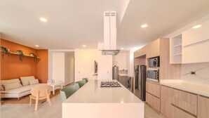 A modern kitchen with a central island, built-in appliances, and a dining area with a sofa and chairs. - w Charming 3BR w Amazing Deco in Medellin (Medellín)