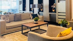 Un salon moderne avec un canapé, des fauteuils, une table basse et une grande fenêtre.