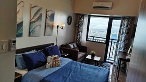 Une chambre d’hôtel avec un lit, un canapé, une petite table et une fenêtre donnant sur la ville.