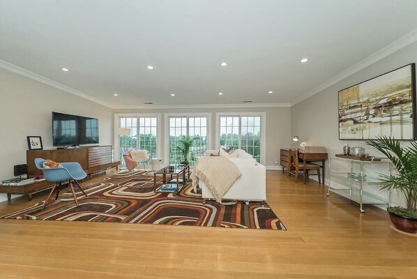 A modern living room with a sofa, a TV, a coffee table, and a large window. - Retro Modern 2 Bdrm 2 Bath Condo (Cincinnati)