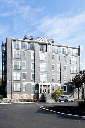 A multi-story building with a symmetrical facade, balconies, and a central entrance with steps. - Retro Modern 2 Bdrm 2 Bath Condo (Cincinnati)