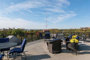 A rooftop patio with outdoor furniture, a round table, and potted yellow flowers. - Retro Modern 2 Bdrm 2 Bath Condo (Cincinnati)