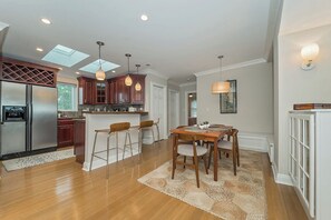 A modern kitchen with a central island, bar stools, pendant lighting, and a dining area with a rug. - Retro Modern 2 Bdrm 2 Bath Condo (Cincinnati)