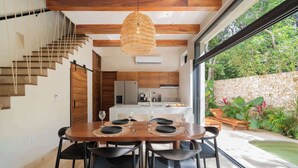 A modern dining area with a wooden table, black chairs, and a hanging light fixture.