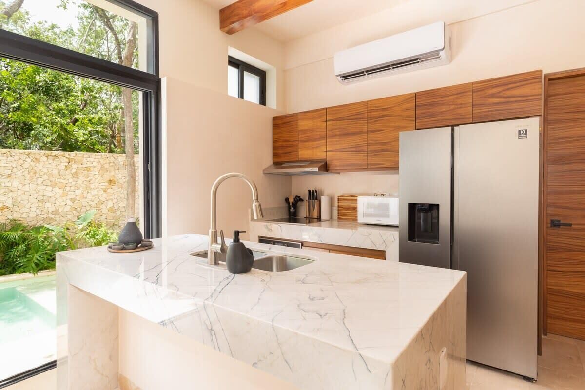 Una cocina moderna con encimera de mármol, electrodomésticos de acero inoxidable y armarios de madera.