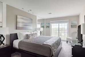 A modern bedroom with a large bed, bedside tables, a TV, and artwork on the walls.