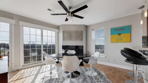 A modern kitchen with a black countertop, white chairs, and a ceiling fan. - Penthouse Style Condo with City View (Cincinnati)