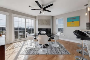 A modern kitchen with a black countertop, white chairs, and a ceiling fan. - Penthouse Style Condo with City View (Cincinnati)
