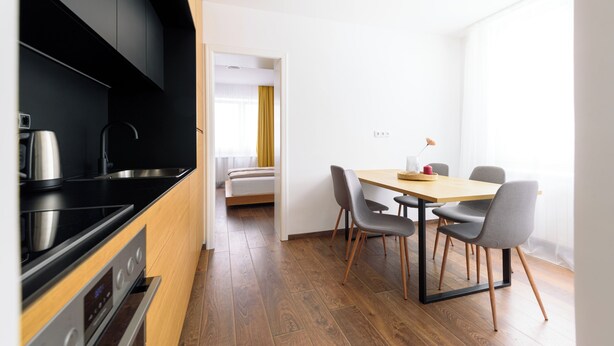 A modern kitchen with black cabinets, stainless steel appliances, and a wooden dining table with chairs. - Tim 3 (Belgrade)